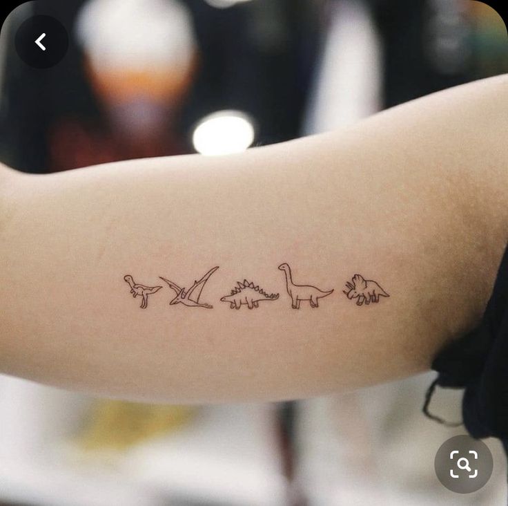 a woman's arm with an outline of dinosaurs on the back of her arm