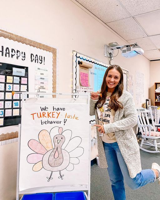 a woman standing in front of a turkey drawing on a sign that says happy day