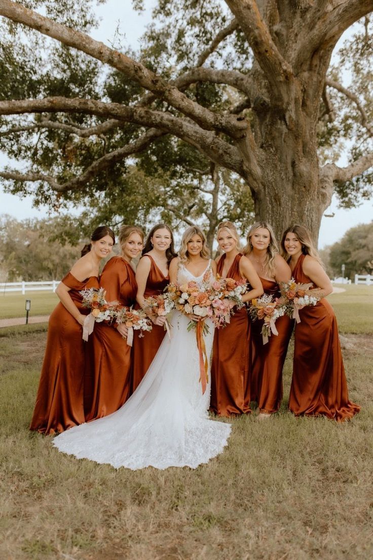 a group of women standing next to each other in front of a tree