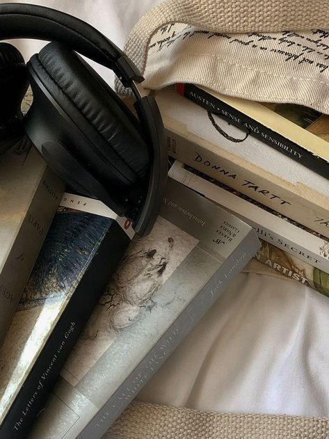 books and headphones on top of a bed next to each other with the covers pulled back