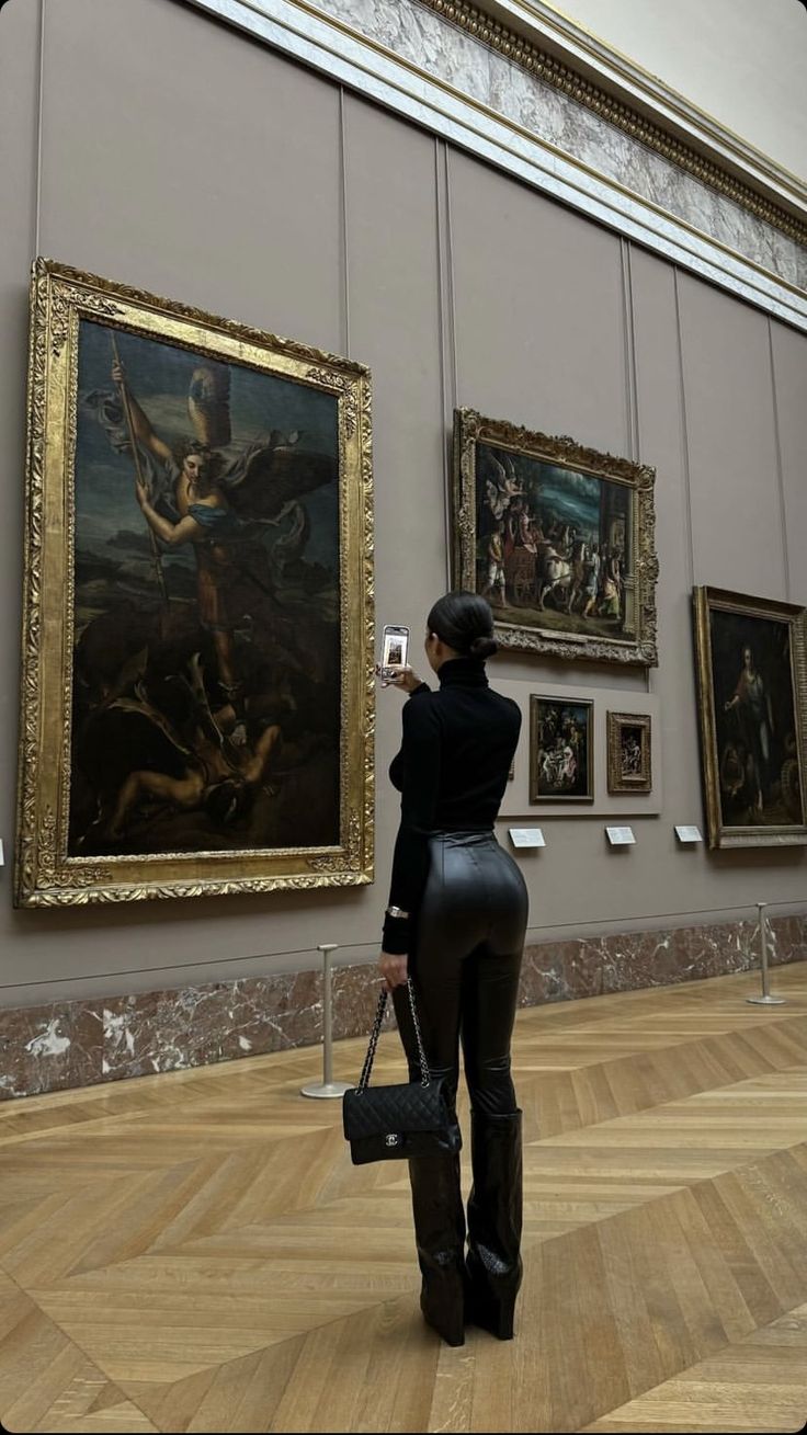 a woman taking a photo of some paintings