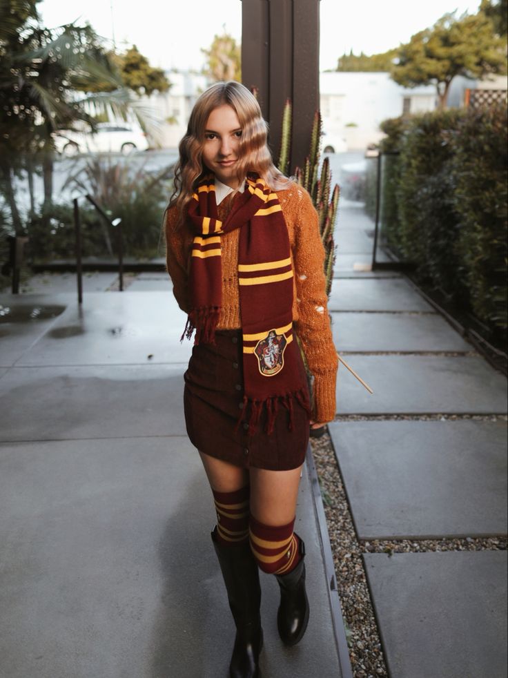 a woman dressed in harry potter costume standing on the sidewalk with her hands behind her back