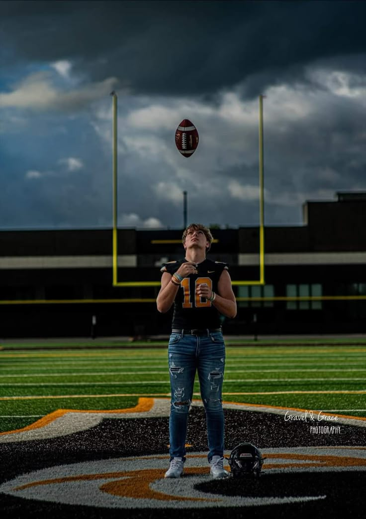 a man standing on top of a field with a football in the air above his head