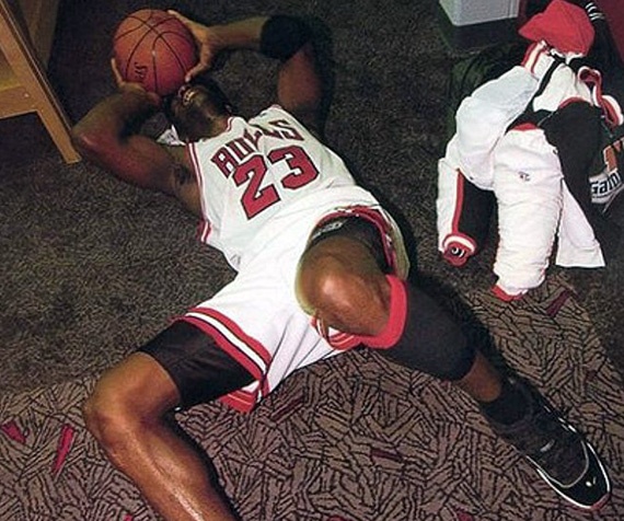 a man laying on the floor with a basketball in his hand and another person sitting next to him