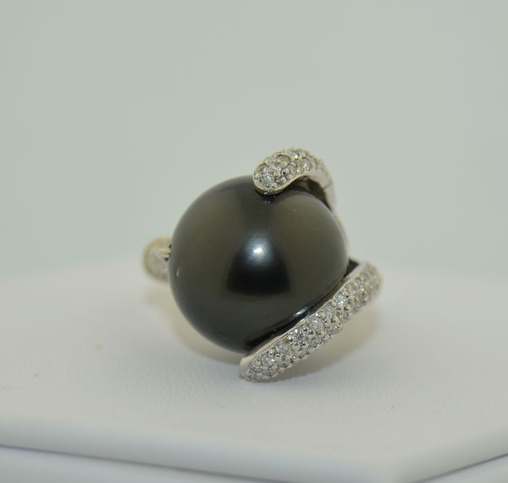 This is an impressively large pearl ring. The pearl is a south Sea Black Tahitian Pearl. The pearl is drilled and mounted with pave diamond accents. The small prong is drilled on the side and the fingers of diamonds are securing the pearl with no movement. This pearl is big, measuring in at 15.5 mm. It is a deep grey/black, perfectly round. There are a couple of natural dimples on the side not the top of the pearl as photographed The setting is 14K White gold, not hallmarked but tested and guara Formal Black Tahitian Pearl Ring, Tahitian Pearl Ring With Diamond Accents Fine Jewelry, Classic Tahitian Pearl Ring With Diamond Accents, Fine Jewelry Tahitian Pearl Ring With Diamond Accents, Tahitian Pearl Ring With Diamond Accents, Luxury Tahitian Pearl Ring With Diamond Accents, Elegant Tahitian Pearl Ring With Diamond Accents, Formal Tahitian Pearl Ring With Diamond Accents, Tahitian Pearl Ring