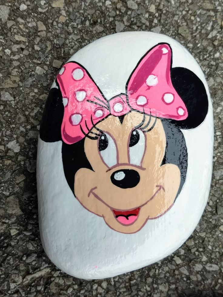 a painted rock with a minnie mouse face and pink bow on it's head