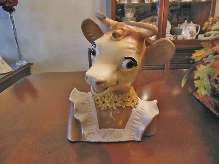 a ceramic figurine of a deer wearing a yellow collar on a wooden table