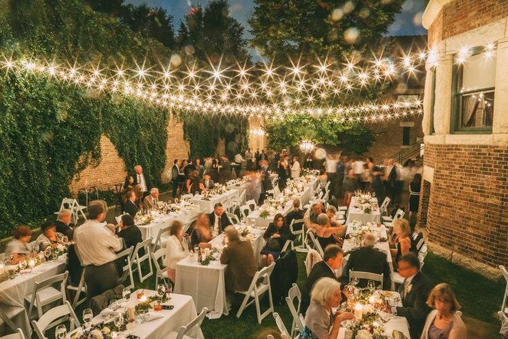 a group of people sitting at tables under string lights