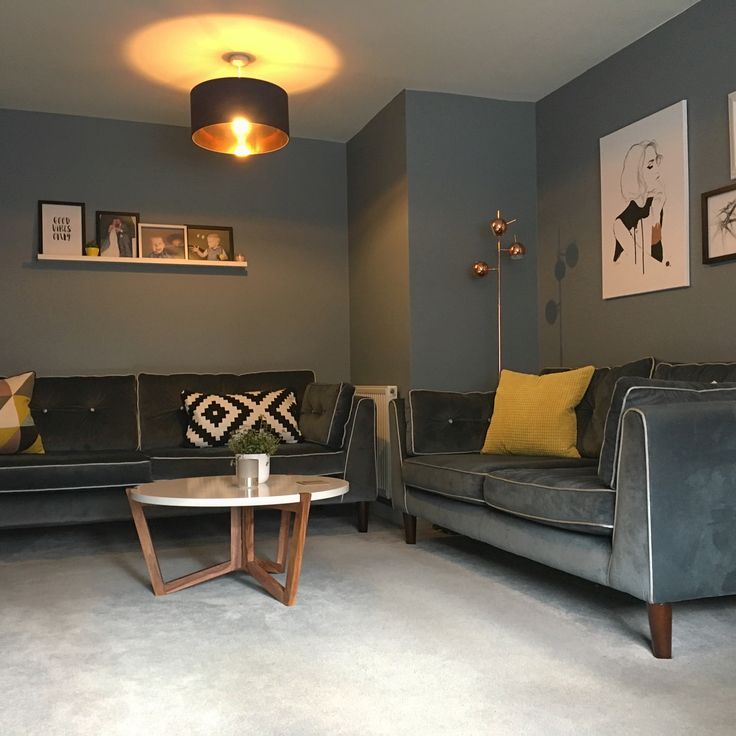 a living room with two couches, a table and pictures on the wall behind them