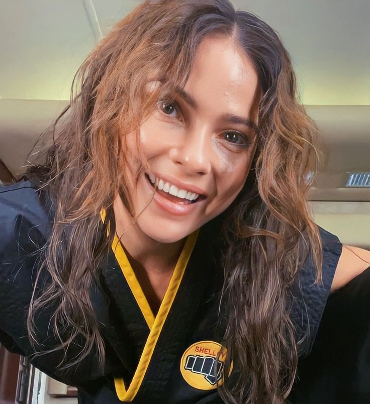 a woman with long hair and a badge on her neck is smiling at the camera