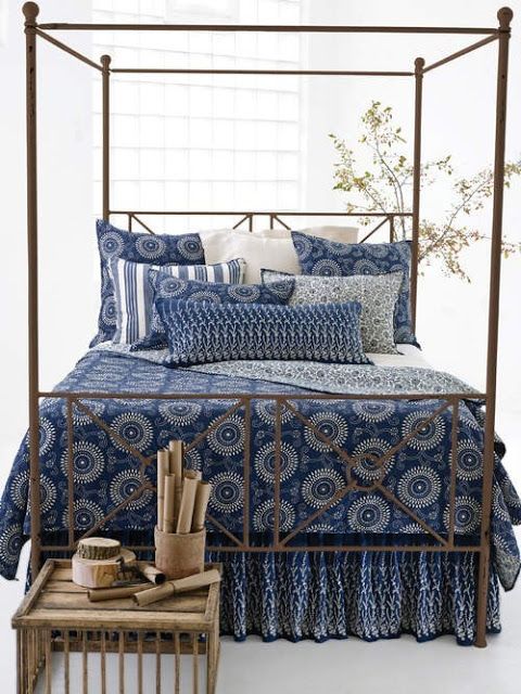 a bed with blue and white bedspread, pillows and pillow cases on it