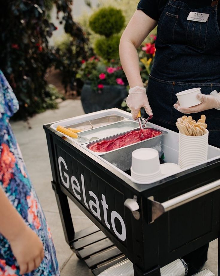 two people are serving themselves food from a gelato cart