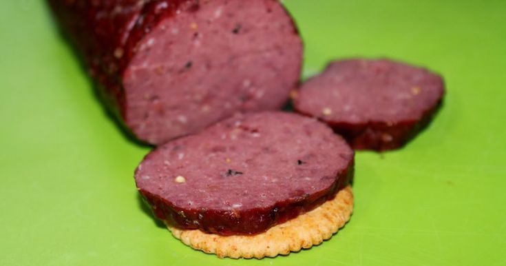 a close up of some food on a green surface with a cracker in the foreground