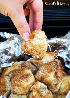 a hand is picking up some food out of the foil