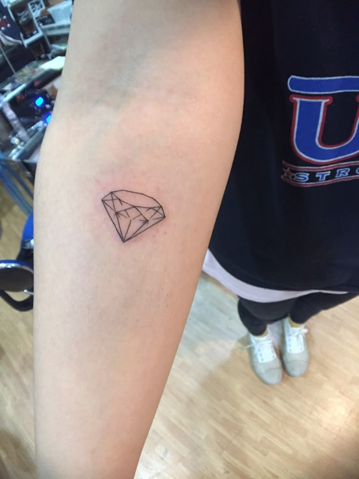 a woman's arm with a diamond tattoo on the left side of her leg