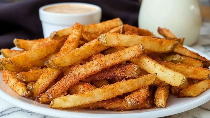 a white plate topped with french fries next to a glass of milk