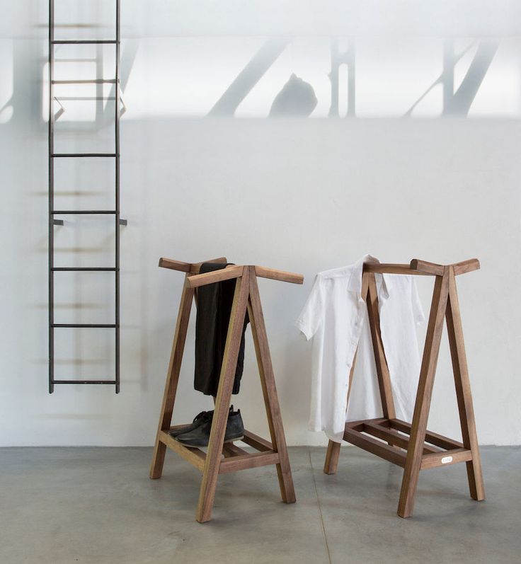 two wooden stools sitting next to each other in front of a white wall and ladder