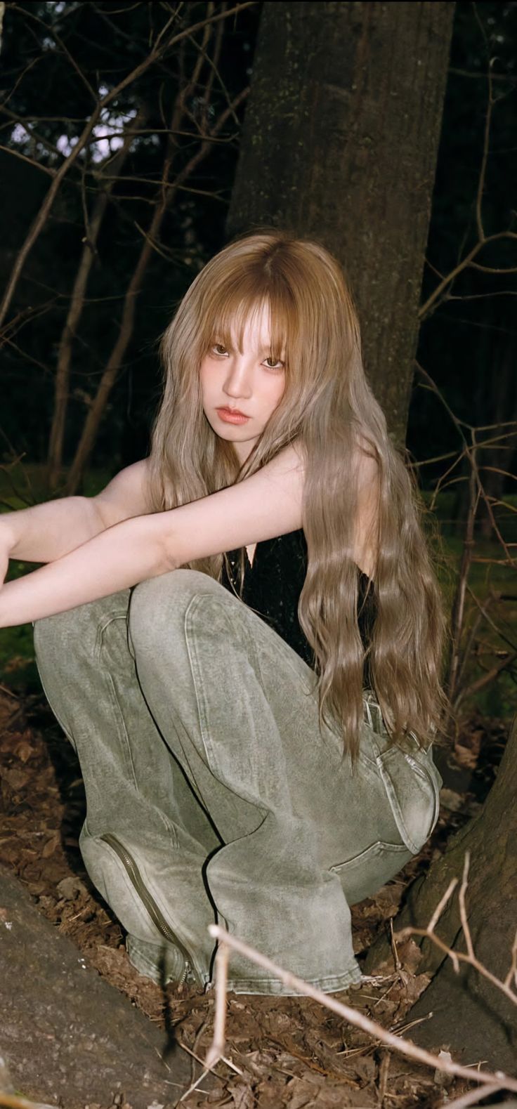 a young woman crouching down in the woods