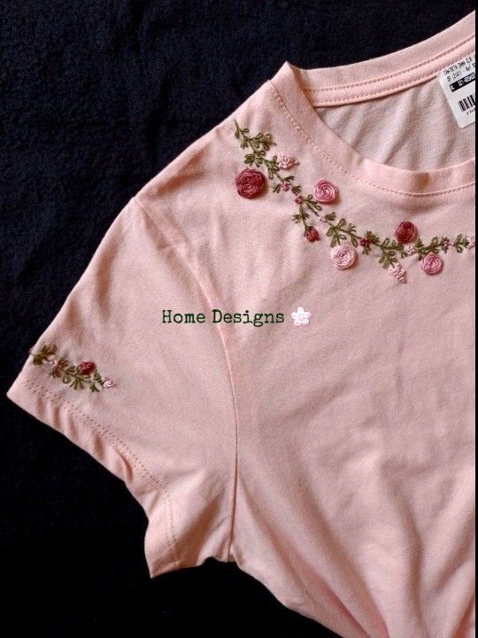 a pink shirt with flowers on it sitting on a black surface