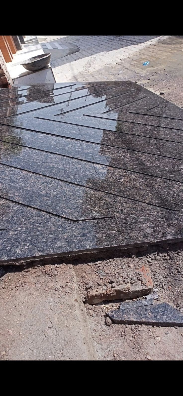 a broken umbrella laying on the ground next to a building with water coming out of it