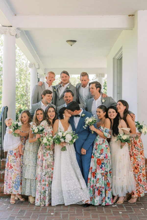 a group of people standing next to each other in front of a white building with flowers