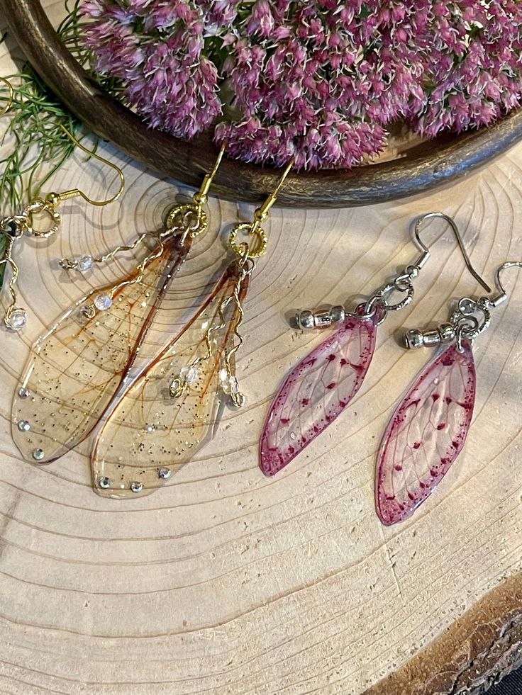 Handcrafted resin and acetate wings with twisted wire and glass beads, glitter and rhinestone accents Clear Resin Jewelry With Ear Wire, Resin Jewelry With Matching Earrings For Party, Whimsical Resin Jewelry For Party, Whimsical Resin Jewelry With Ear Wire, Handmade Wing-shaped Jewelry For Party, Clear Resin Earrings, Wire Wings, Fairy Wing Earrings, Sun Designs