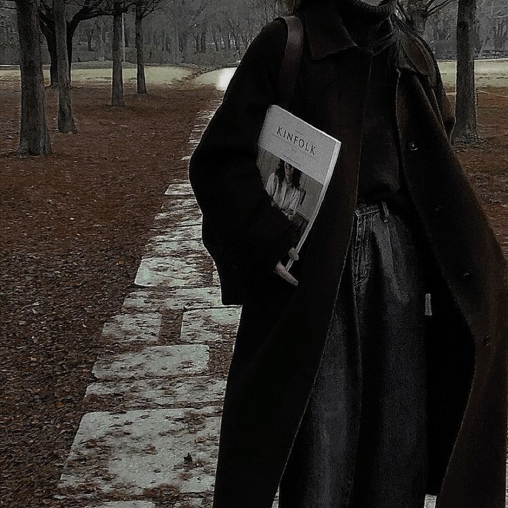 a man standing in the rain with an umbrella over his head and a book on his shoulder