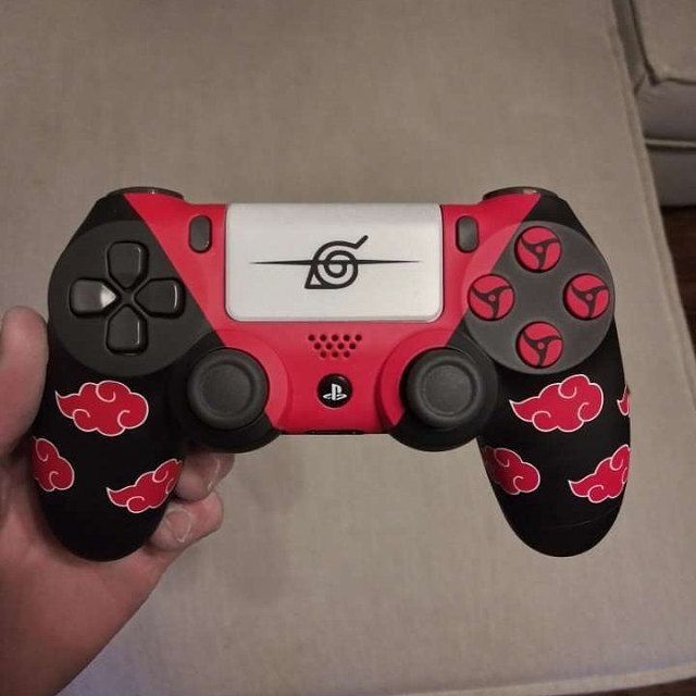 a hand holding a red and black video game controller