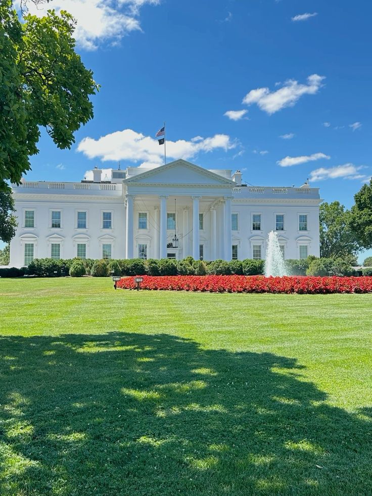 the white house in washington d c with red and yellow flowers on the front lawn