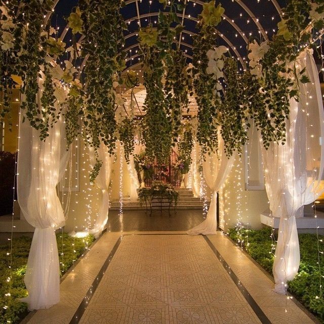 an outdoor walkway decorated with lights and greenery