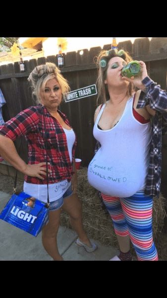 two women dressed in costumes standing next to each other near a fence and eating food