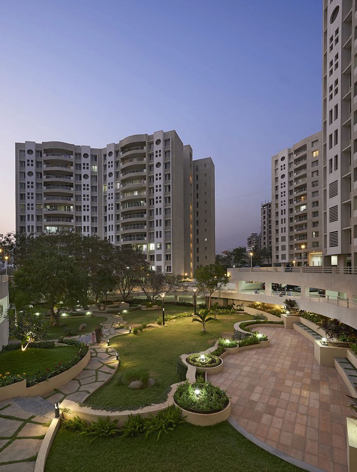 an apartment building with landscaping in the foreground and lawn area at dusk, surrounded by tall buildings