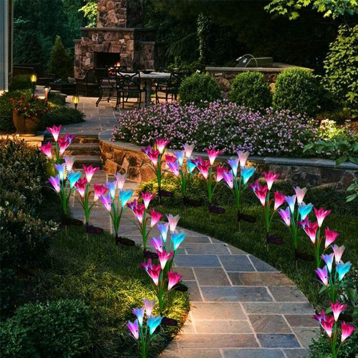 colorful flowers are in the middle of a garden path at night with lights on them