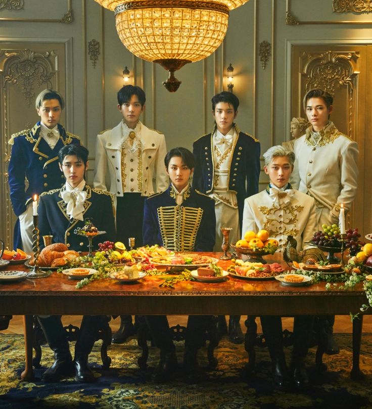 a group of young men standing next to each other in front of a table with food on it