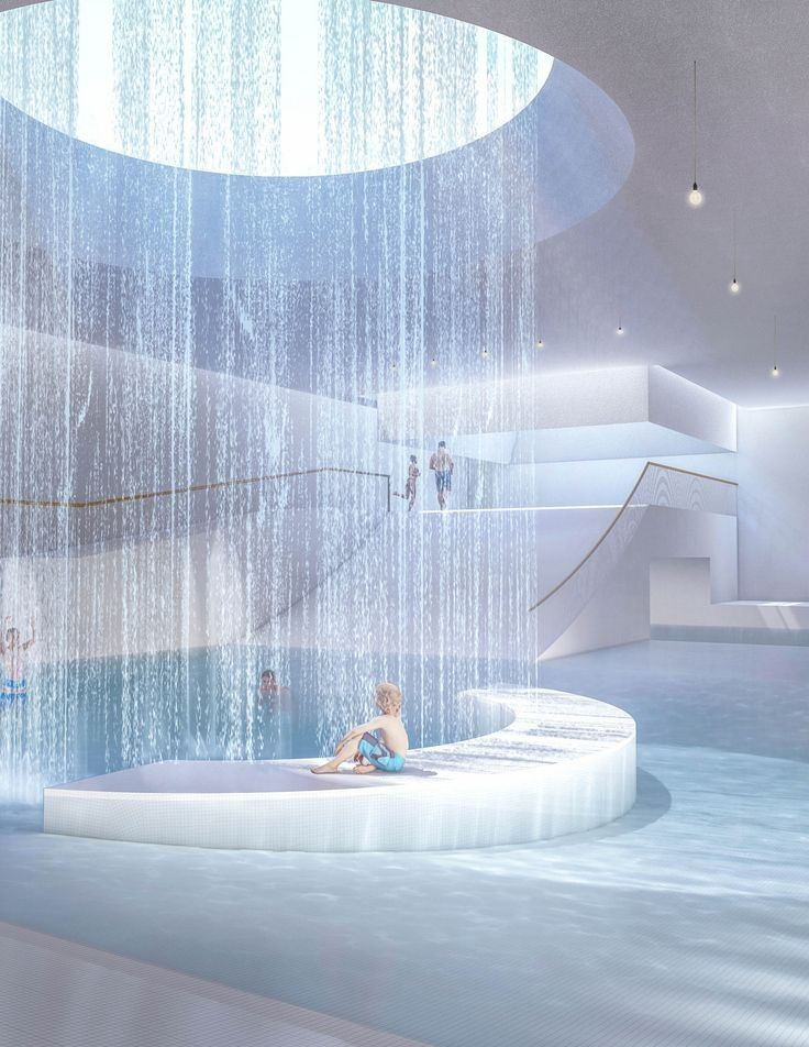 a child is sitting in the middle of an indoor swimming pool with water falling from the ceiling