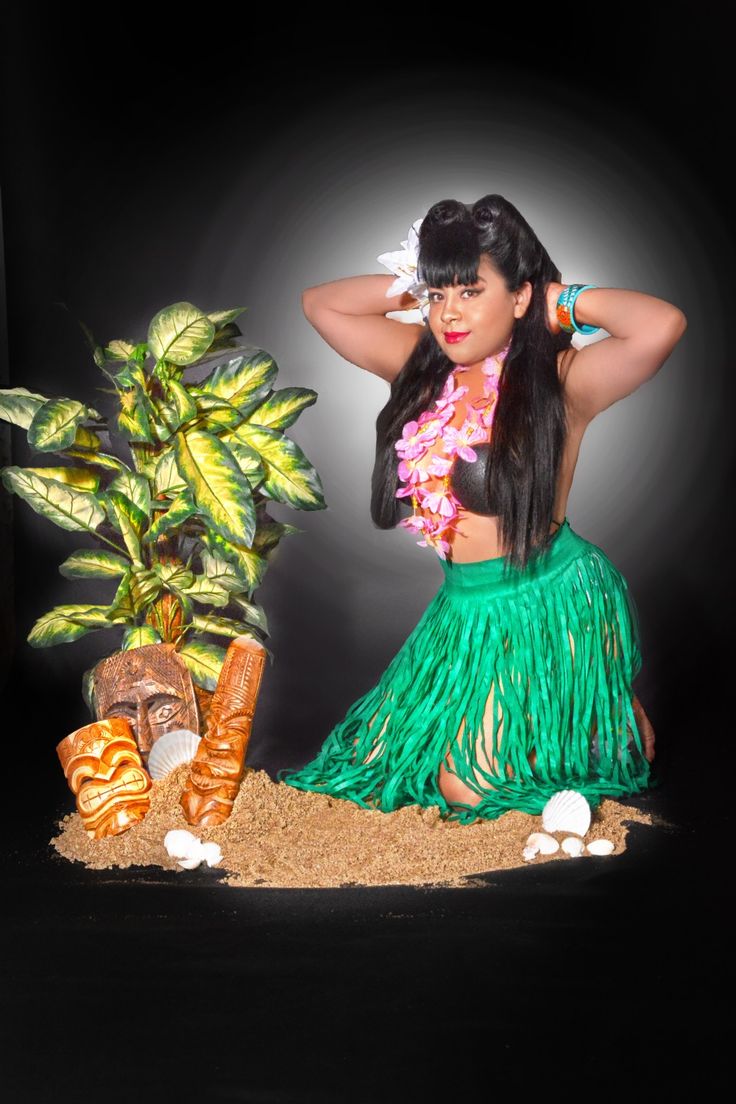 a woman in a hula skirt next to a potted plant