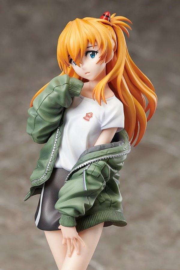 a doll with orange hair is posed on a white surface and wearing a green jacket