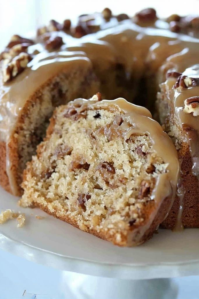 a bundt cake with frosting and nuts on top sitting on a white plate