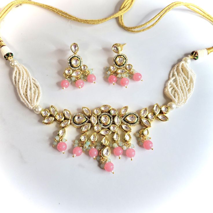 A bright gold and pink kundan necklace set with earrings. Can be worn as a choker or necklace. Pink Necklace For Diwali, Pink Jewelry Sets For Party And Festivals, Bollywood Pink Choker For Diwali, Pink Kundan Choker Jewelry, Pink Kundan Choker For Party, Pink Necklace For Diwali Celebration, Pink Necklace For Diwali Party, Pink Choker For Party And Festivals, Pink Party Choker For Festivals