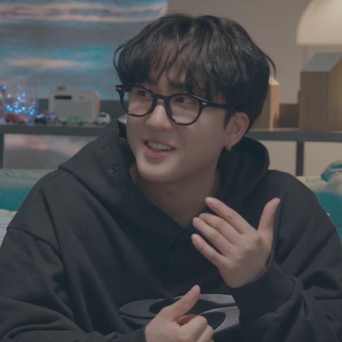 a young man wearing glasses sitting on top of a couch