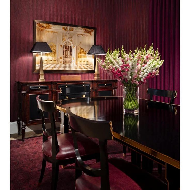 a dining room table with chairs and flowers in a vase on the table next to it