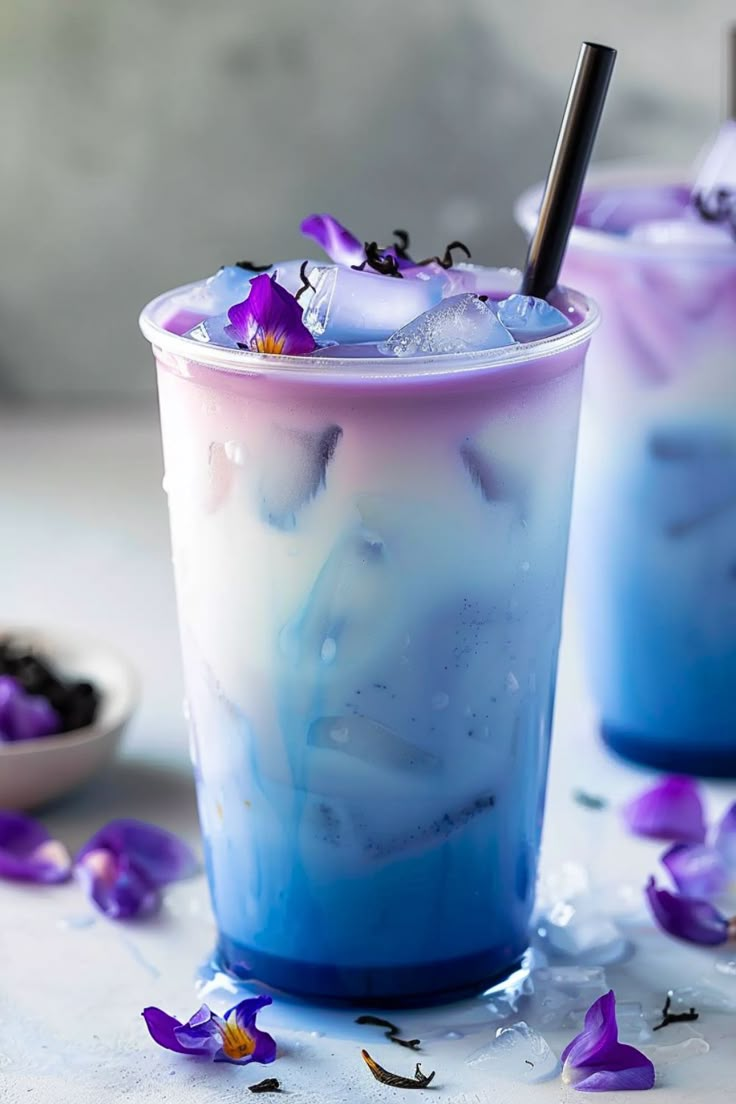 two glasses filled with blue liquid and purple flowers