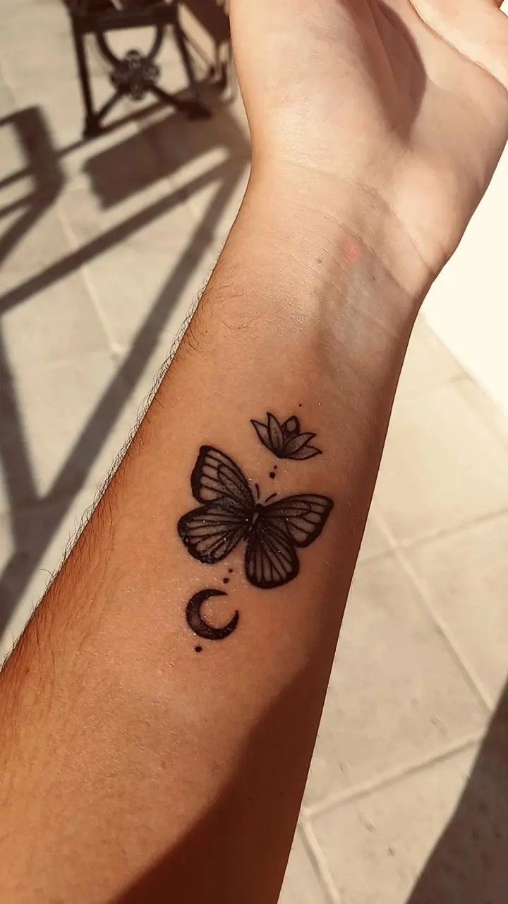 a person's arm with a butterfly tattoo on the left side of their arm