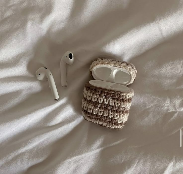 an apple airpods sitting on top of a bed next to headphones and earbuds