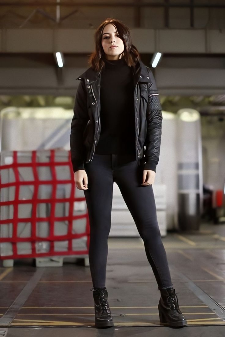 a woman in black jacket and leggings posing for the camera