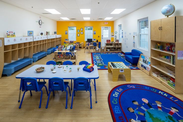 an empty classroom with blue chairs and tables in front of bookshelves on the wall