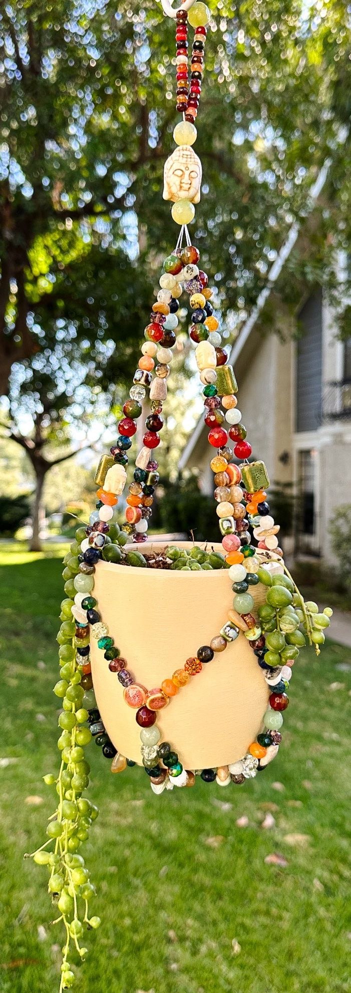 a hanging planter made out of glass beads and other items in front of a house