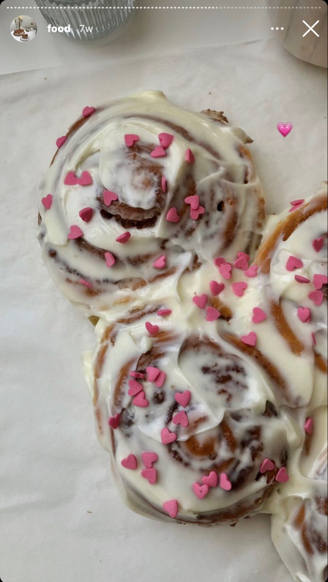 three donuts with white icing and pink sprinkles on top of paper