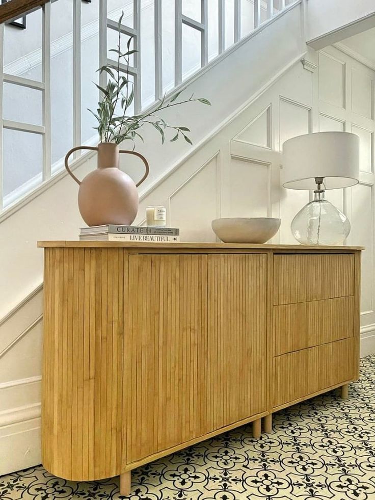 a table with a vase on top of it next to a stair case and lamp