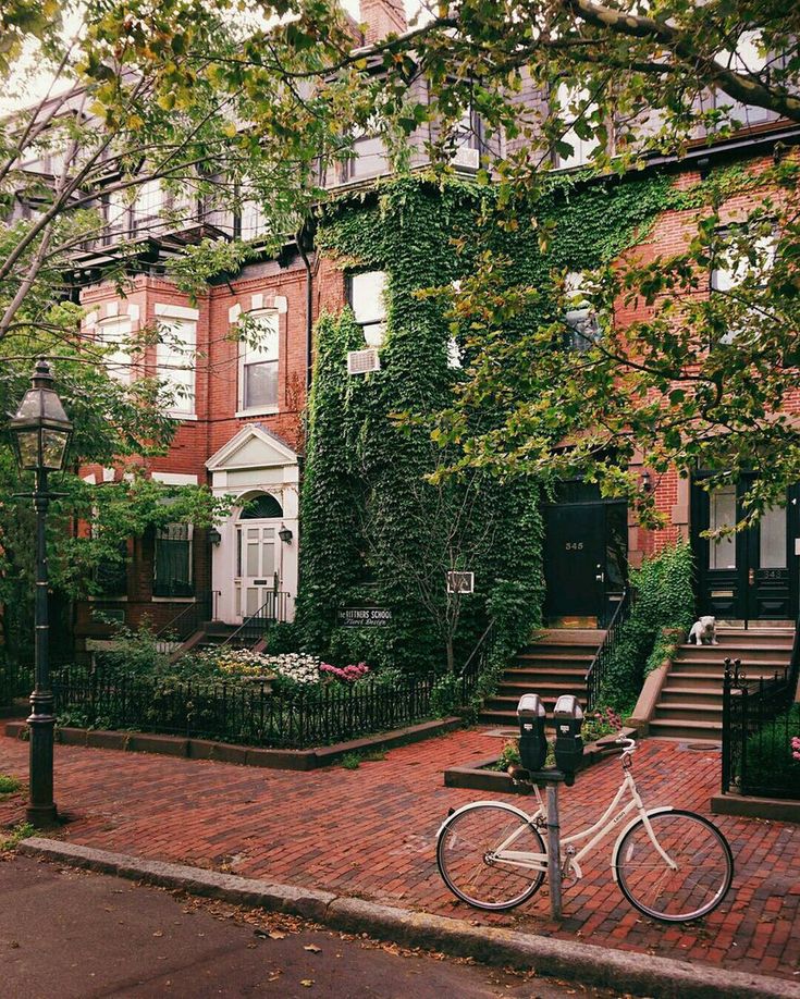 a bicycle parked on the side of a brick road in front of a row of houses